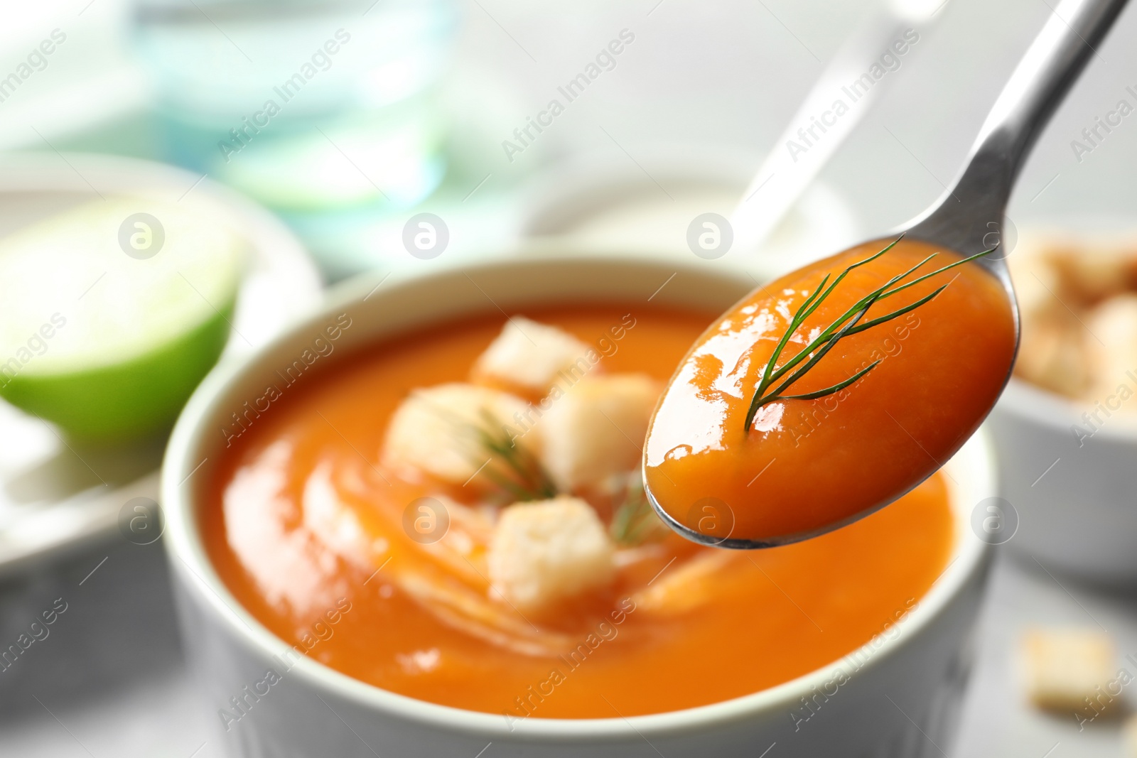 Photo of Spoon with tasty sweet potato soup over table, closeup. Space for text