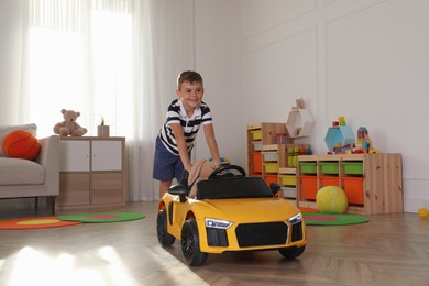 Cute little boy playing with big toy car and stuffed bunny at home