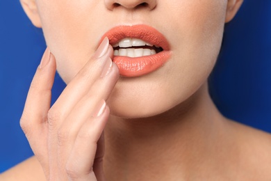 Photo of Young woman wearing beautiful lipstick on color background, closeup