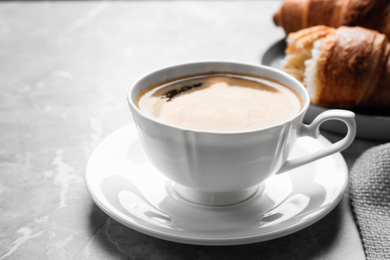 Photo of Coffee and tasty croissants on light grey marble table, closeup