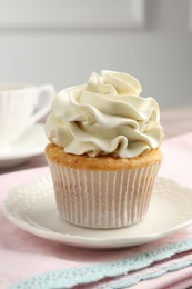 Photo of Tasty cupcake with vanilla cream on table, closeup