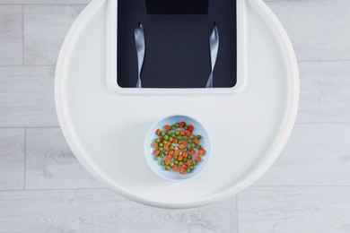 Photo of High chair with healthy baby food served on white tray indoors, top view