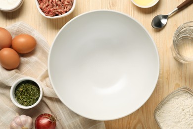 Photo of Bowl and different products on wooden table, flat lay