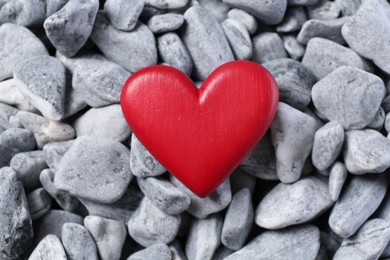Photo of Red decorative heart on grey stones, top view