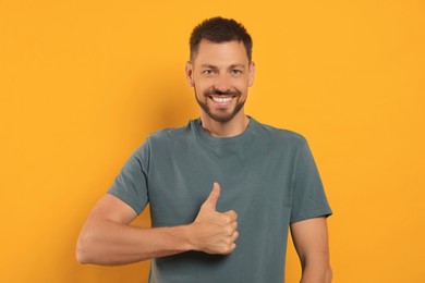 Photo of Man showing thumb up on orange background