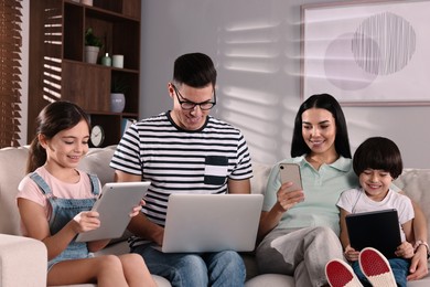 Photo of Internet addiction. Family with different gadgets on sofa at home