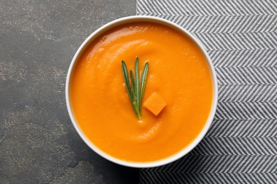 Photo of Bowl of tasty pumpkin soup on gray background, top view