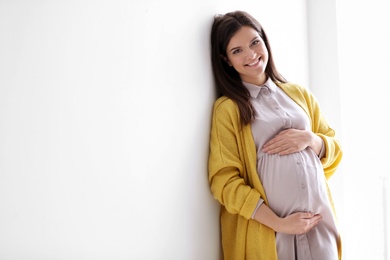 Photo of Young pregnant woman in casual clothes on light background