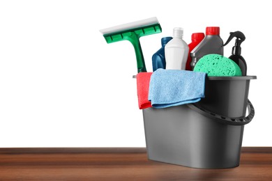 Photo of Grey bucket with car care products on wooden table against white background