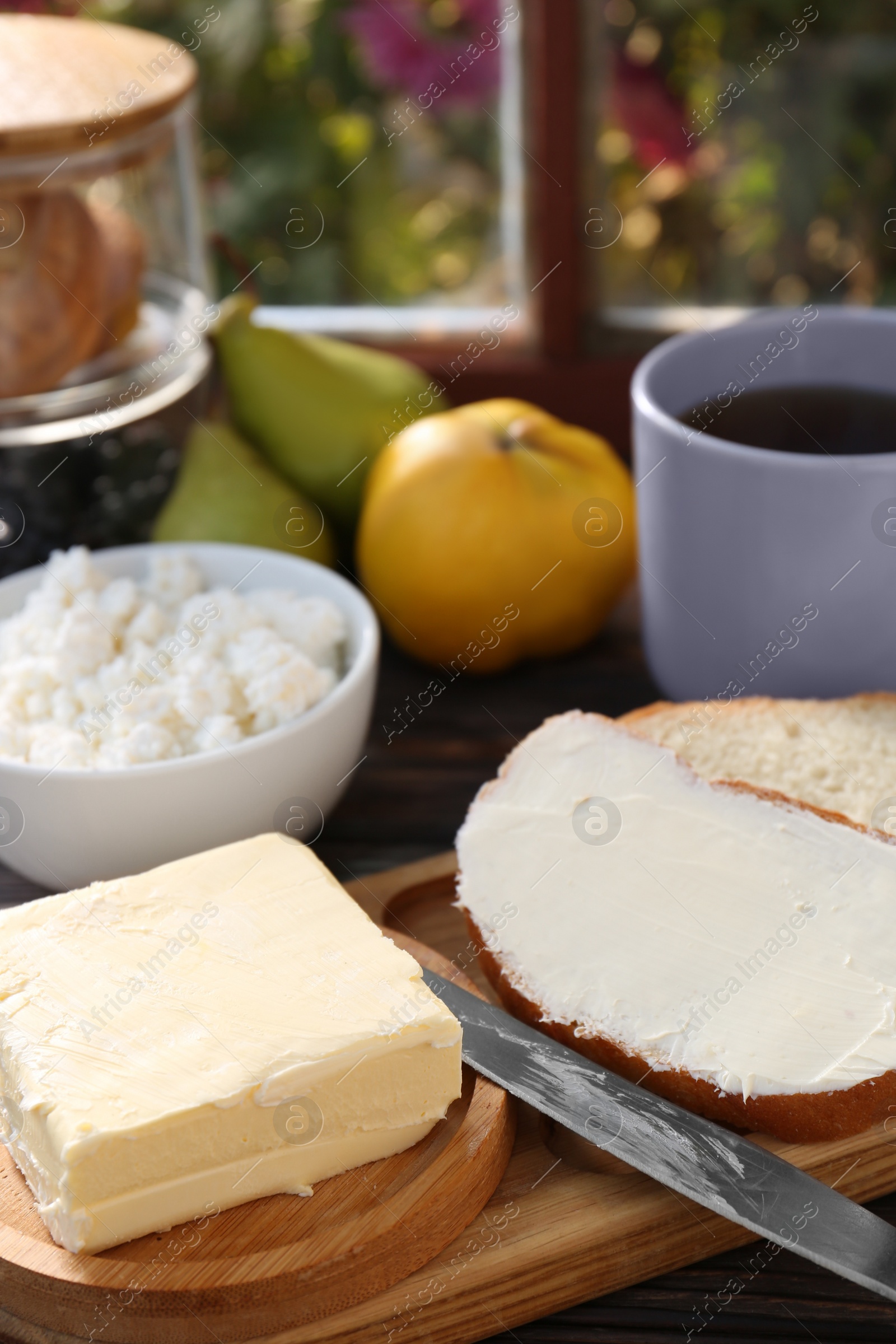 Photo of Tasty homemade butter, bread slices and tea on wooden table, closeup