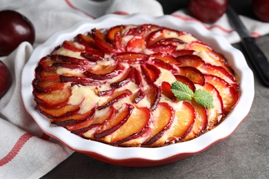 Delicious cake with plums on grey table, closeup