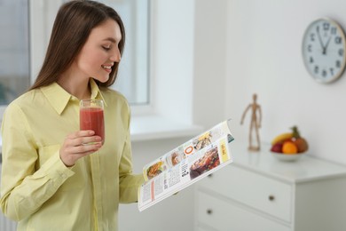 Photo of Beautiful young woman with delicious smoothie reading magazine at home. Space for text