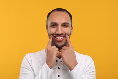 Photo of Portrait of smiling man with healthy clean teeth on orange background