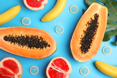 Photo of Flat lay composition with condoms and exotic fruits on blue background. Erotic concept