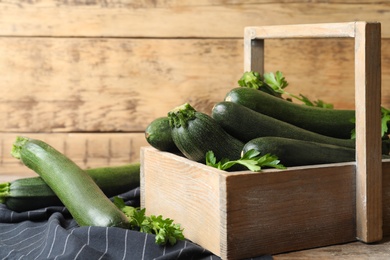 Photo of Crate with green zucchinis and parsley on table