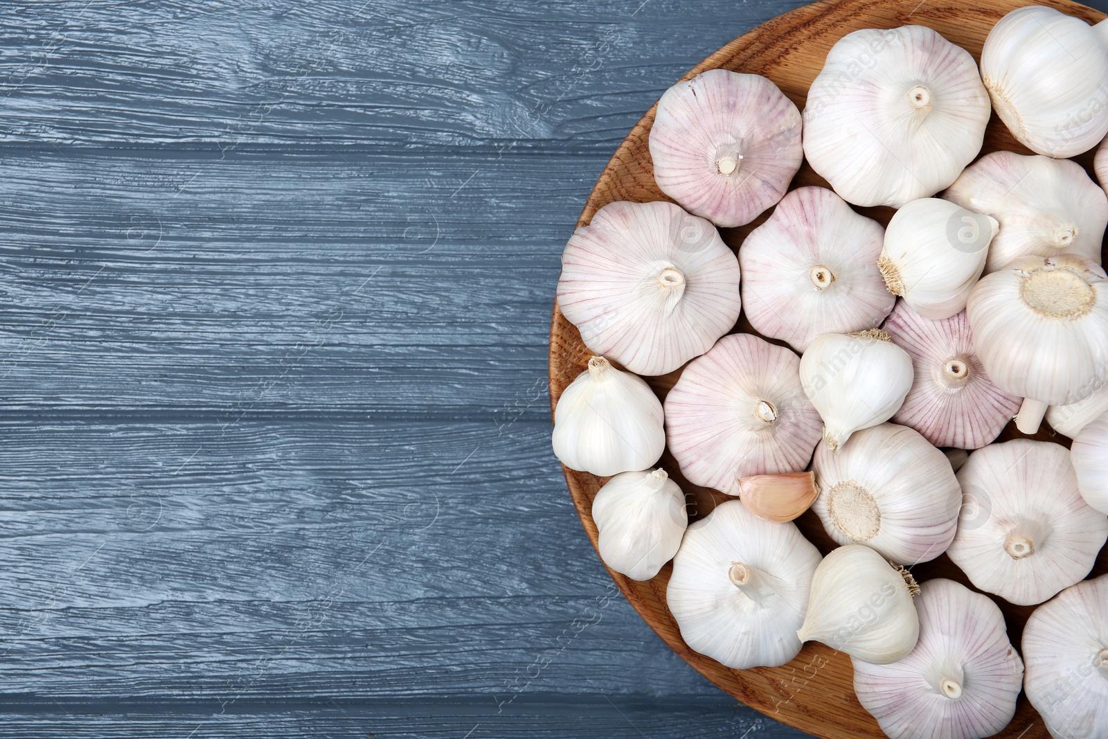 Photo of Plate with fresh garlic bulbs on wooden background, top view