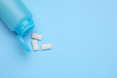 Photo of Jar with chewing gums on light blue background, flat lay. Space for text