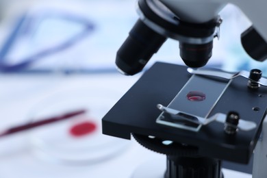 Photo of Modern medical microscope with sample of red liquid in laboratory, closeup. Space for text