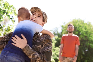 Photo of Female soldier hugging with her son outdoors. Military service