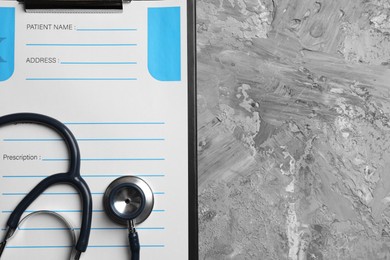 Photo of Medical prescription form with empty fields and stethoscope on grey textured table, top view. Space for text