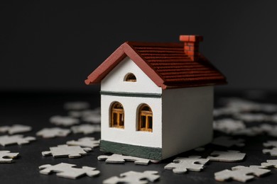 Photo of House model and puzzles on black table depicting destruction after earthquake