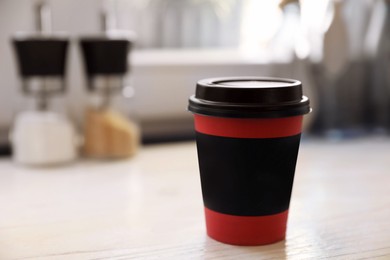 Photo of Hot coffee in takeaway paper cup on wooden table at cafe, space for text