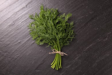 Photo of Bunch of fresh dill on dark textured table, top view