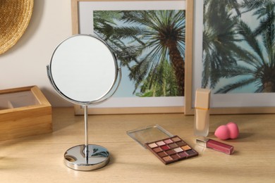 Photo of Mirror, pictures and makeup products on wooden dressing table