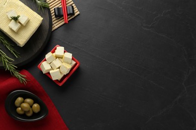Photo of Flat lay with tofu and olives served on black table, space for text. Soya bean curd