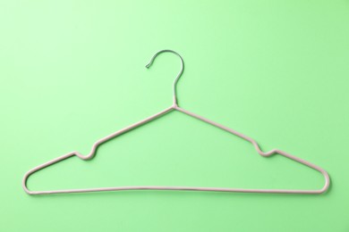 Photo of One pink hanger on light green background, top view