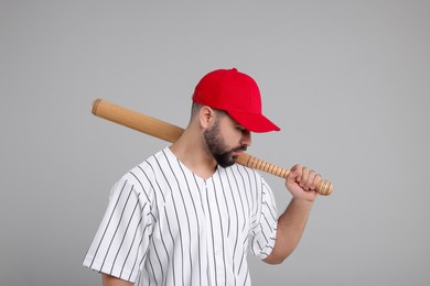 Photo of Man in stylish red baseball cap holding bat on light grey background
