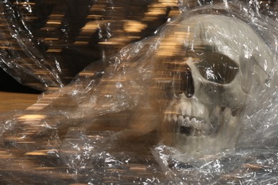 Photo of Human skull with stretch film on blurred background