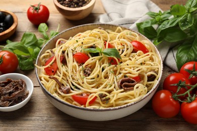 Delicious pasta with anchovies, tomatoes and spices on wooden table