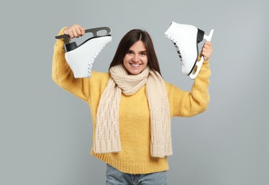 Photo of Happy woman with ice skates on grey background