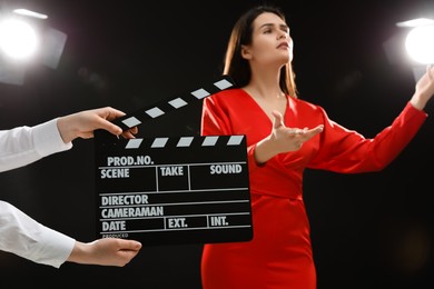 Photo of Emotional actress performing while second assistant camera holding clapperboard on stage, selective focus. Film industry
