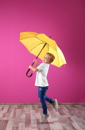 Photo of Little boy with yellow umbrella near color wall