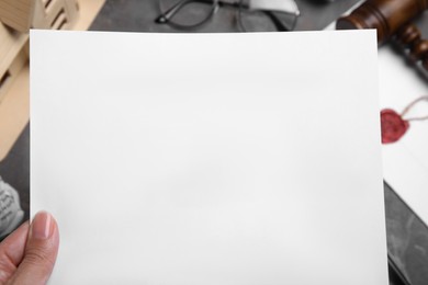 Photo of Woman holding last will and testament at grey table, closeup