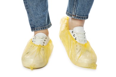 Photo of Woman wearing yellow shoe covers onto her sneakers against white background, closeup
