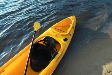 Photo of Beautiful modern yellow kayak with paddle on beach