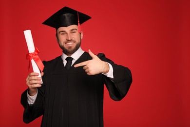 Photo of Happy student with graduation hat and diploma on red background. Space for text