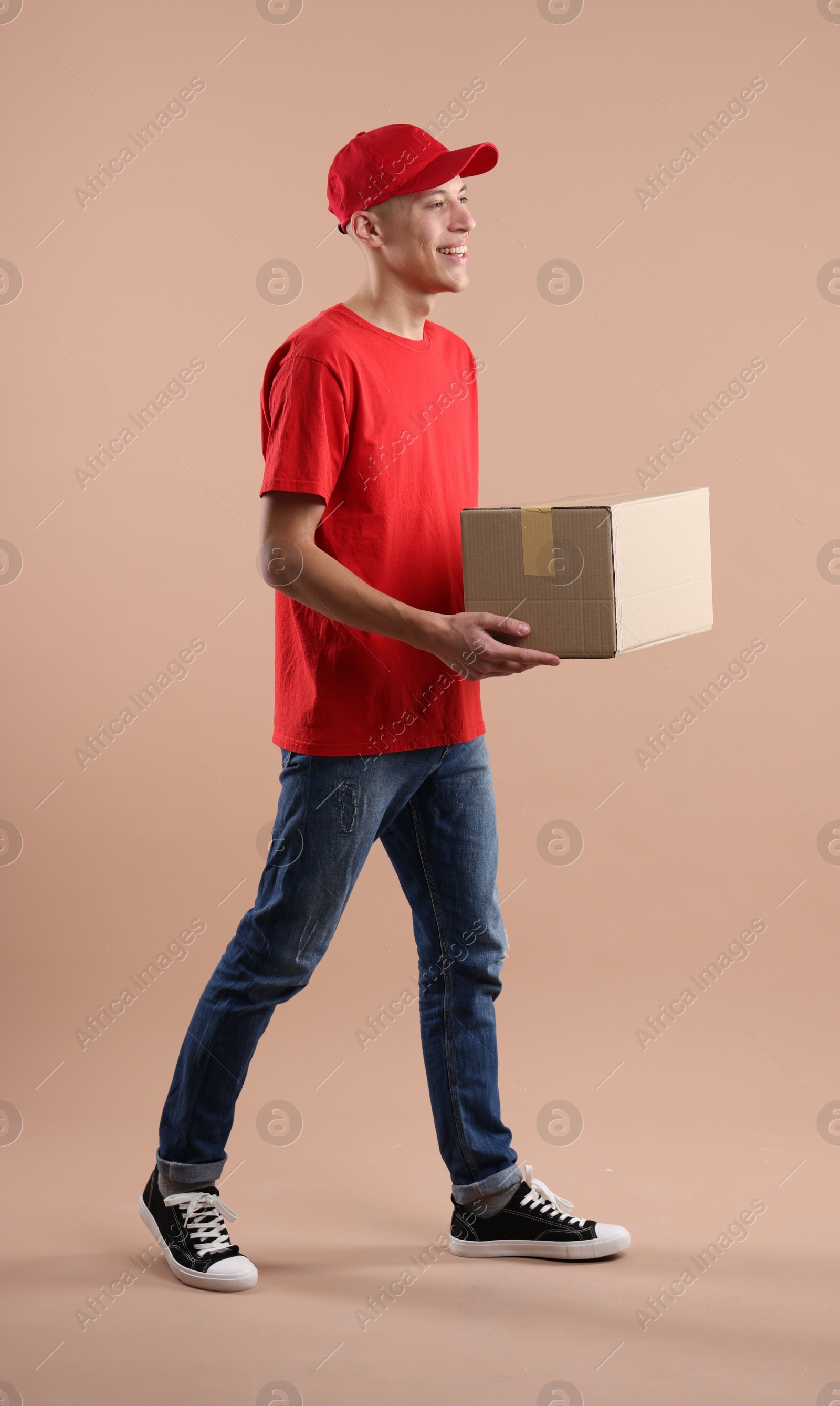 Photo of Happy courier with parcel on beige background