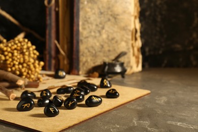 Photo of Many black rune stones on grey table. Space for text
