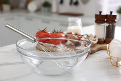 Photo of Whisk, bowl, and different ingredients on white marble table indoors