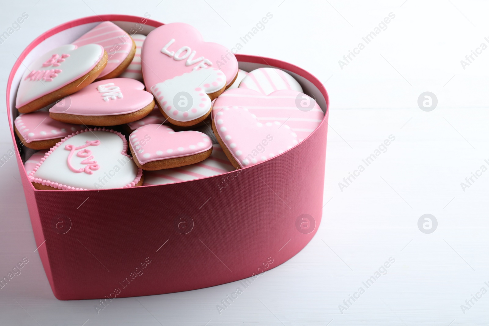 Photo of Delicious heart shaped cookies in box on white table. Valentine's Day