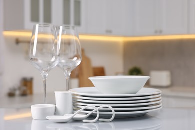 Set of clean dishware and glasses on table in kitchen