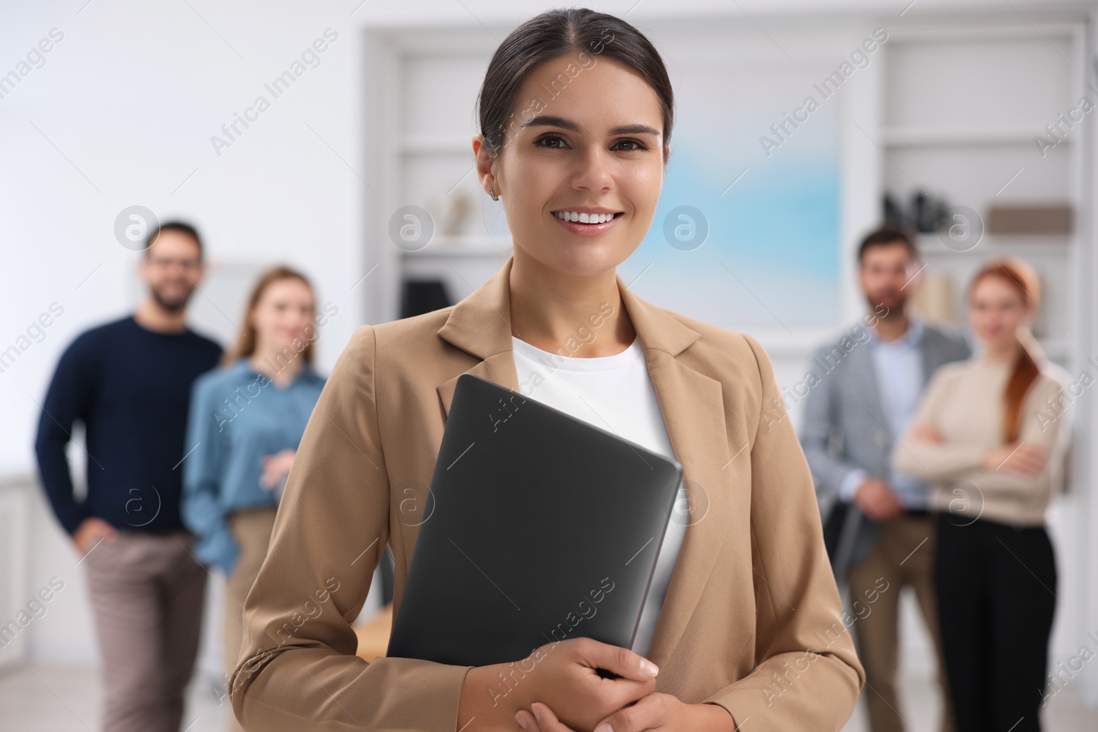 Photo of Portrait of happy businesswoman with laptop and her team in office