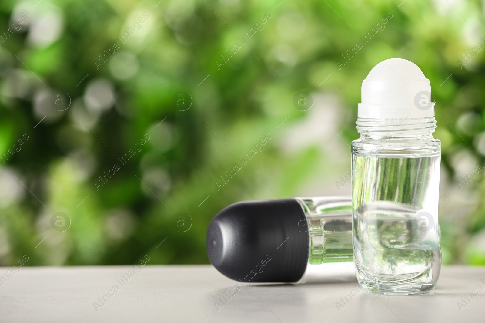 Photo of Different deodorants on white wooden table against blurred background. Space for text