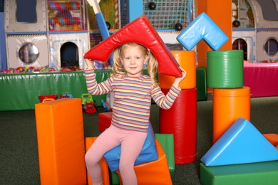 Photo of Cute child playing with colorful building blocks indoors