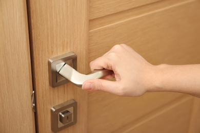 Photo of Woman opening door indoors, closeup of hand