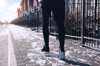 Photo of Man running along street on winter day, closeup. Outdoors sports exercises